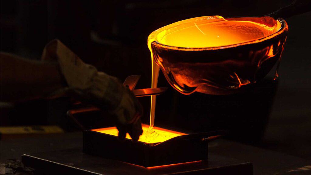 Skilled artisan creating a glass lampshade in a factory setting.