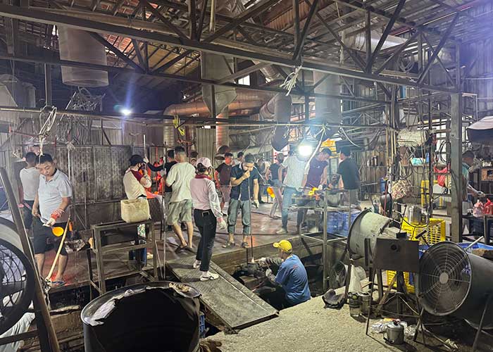 Manufacturing process of glass lampshades at a factory with workers and equipment.