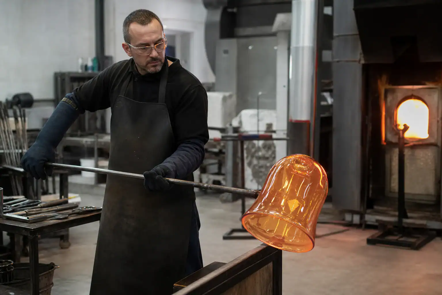 Glass lampshade being crafted in a factory by a skilled artisan.