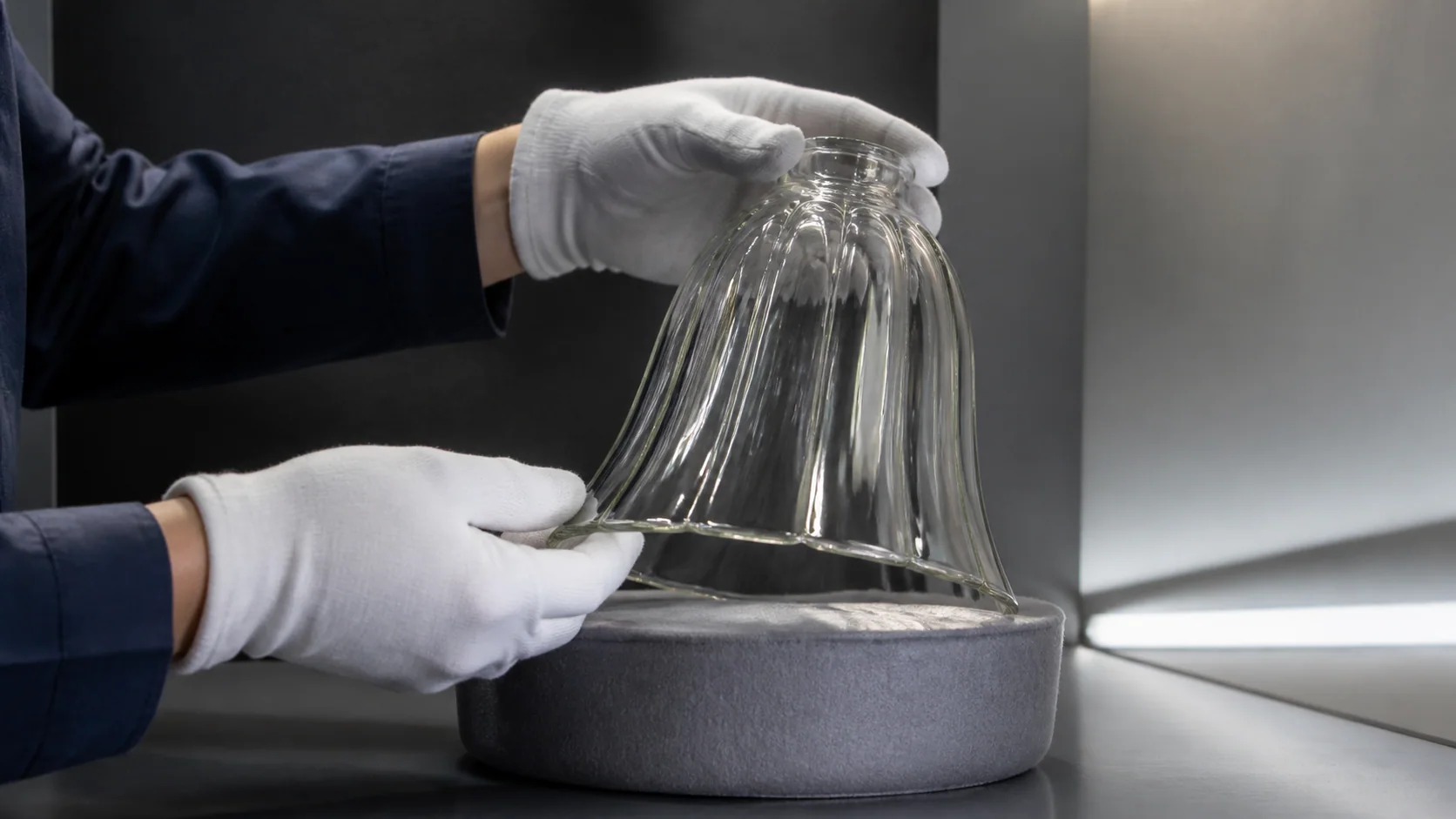 Abat-jour en verre tourné sous une lumière rasante à faible angle lors de l’inspection qualité