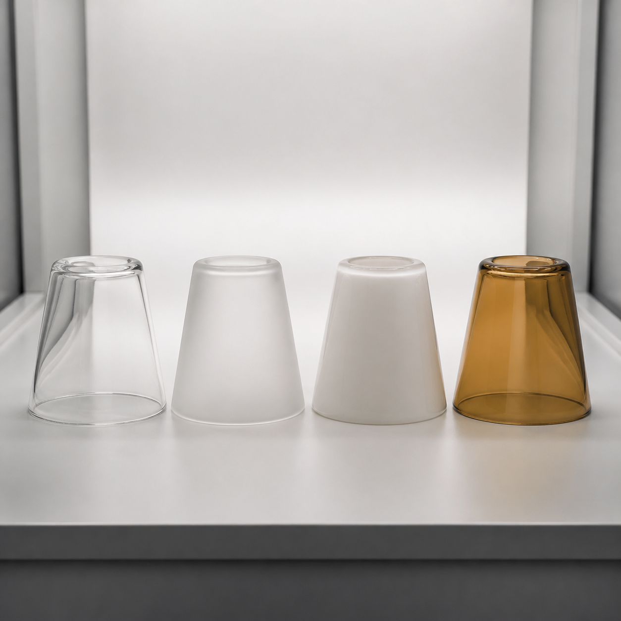 Quatre panneaux d’échantillons de verre montrant les finitions transparent, dépoli, opale et ambre sous la même source lumineuse neutre