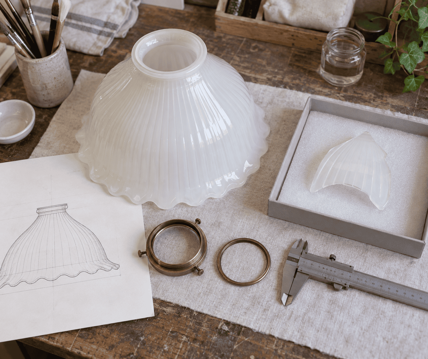 Paralume di ricambio in vetro per lampada da tavolo integro accanto a frammenti di campione protetti, ferramenta originale e strumenti di misurazione