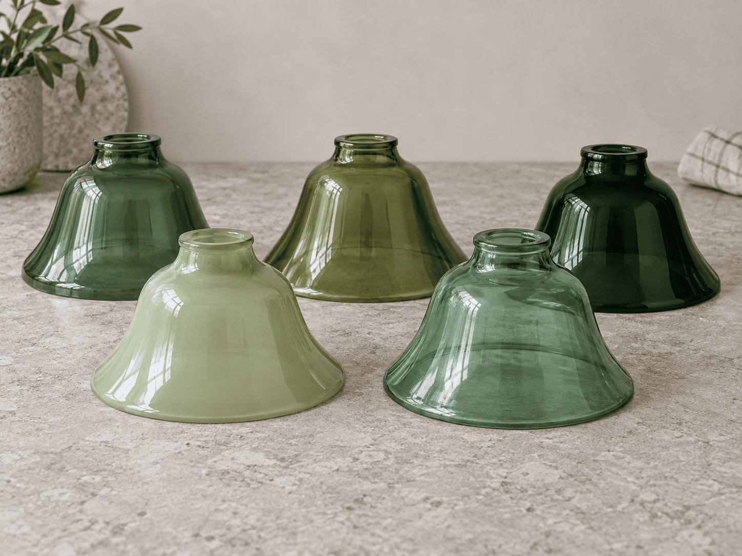 Green glass lamp shade samples ranging from pale sage and olive to bottle green and deep emerald