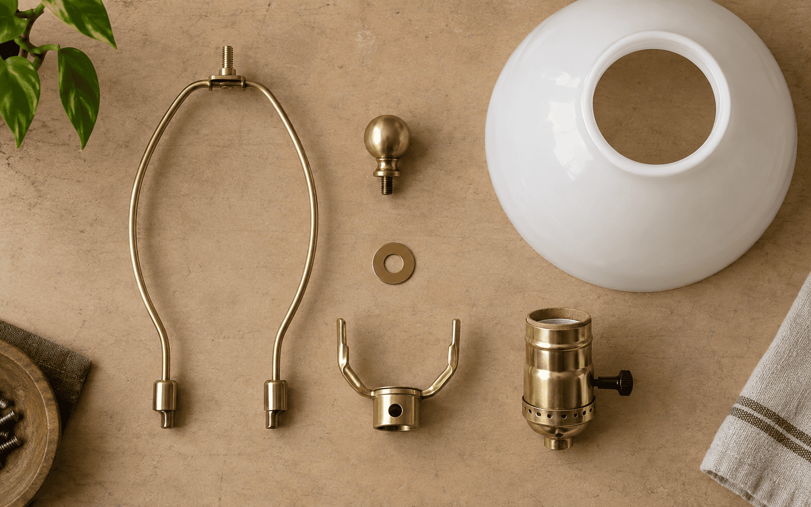 Various brass and ceramic parts for glass lampshades on a beige background.