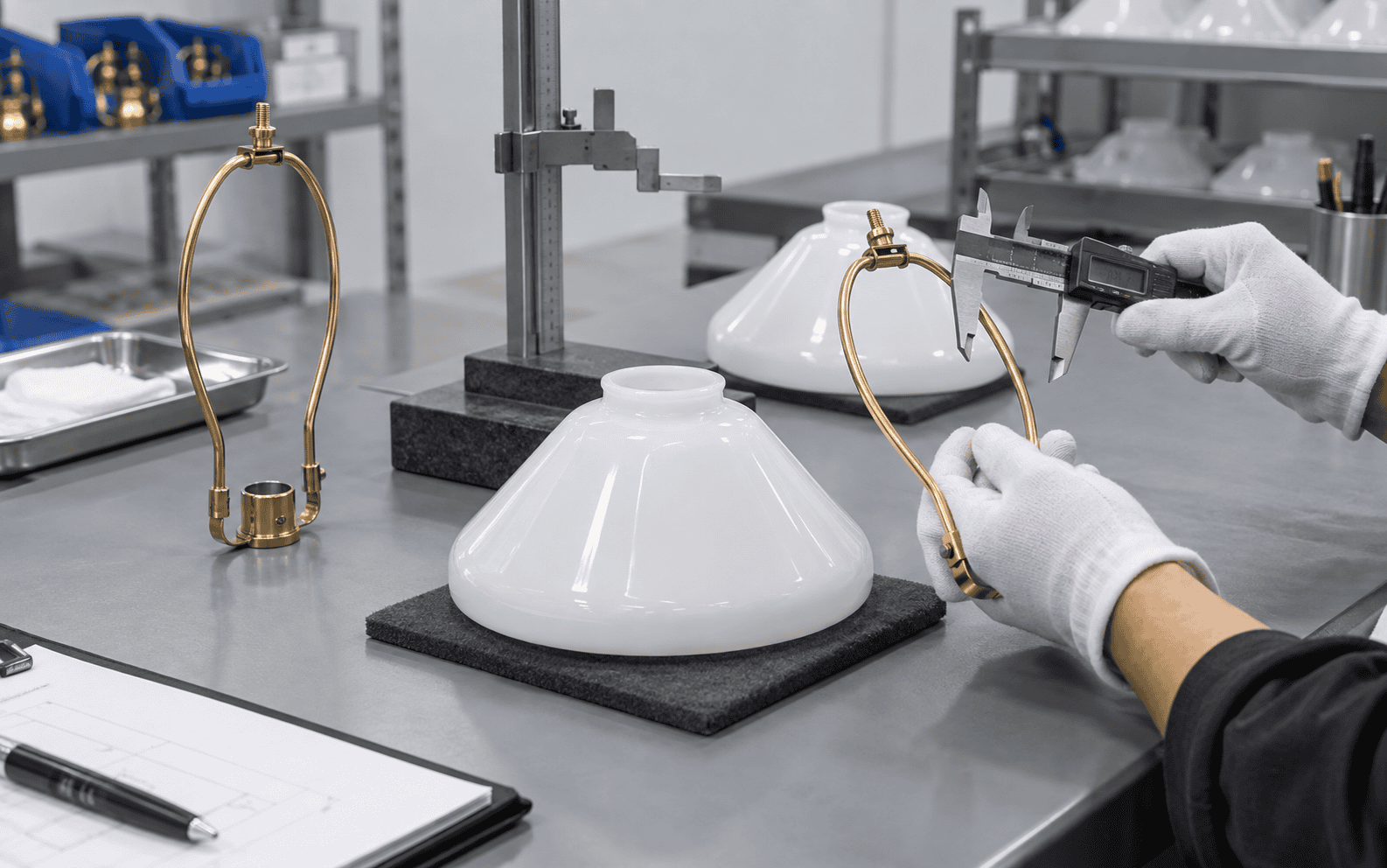 Worker inspecting glass lampshades in a factory setting for quality control.