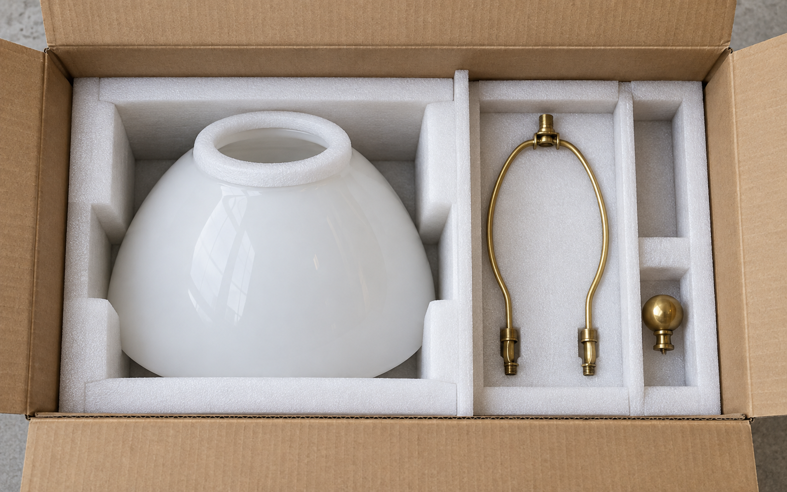 White glass lamp shade, brass harp and finial separated in foam cells and dividers inside a plain export carton