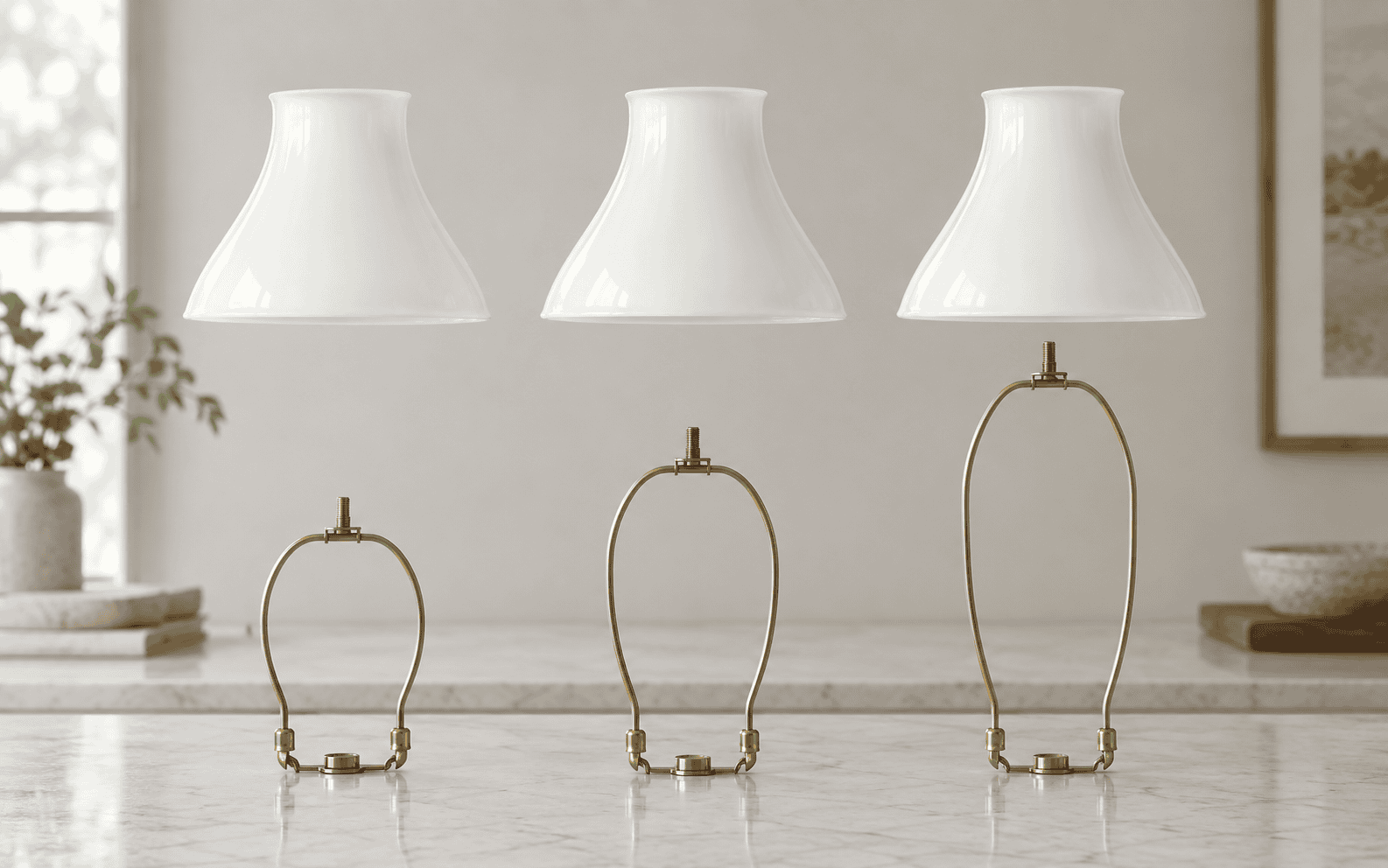 Short, medium and tall brass lamp harps aligned beneath plain glass shades to show different vertical positions
