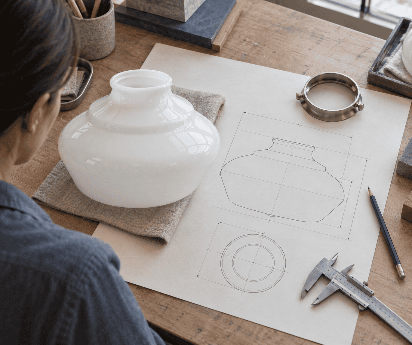 Designer al lavoro su schizzi e progetti di paralumi in vetro.
