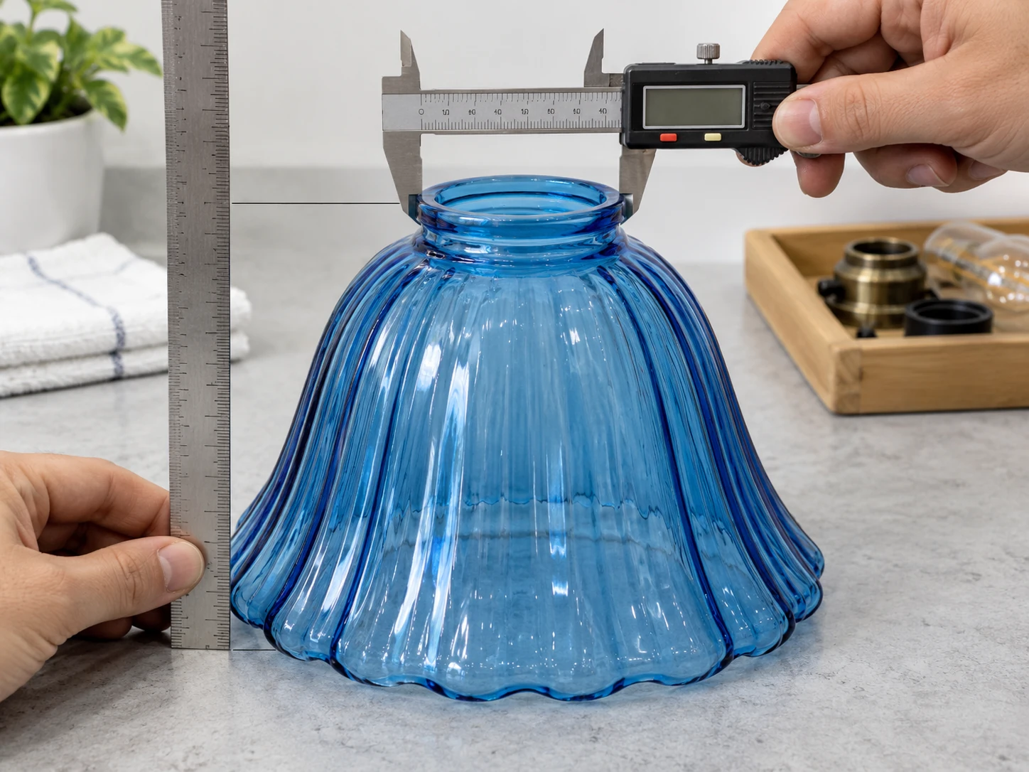 Caliper and ruler positioned to measure a blue glass shade opening and height