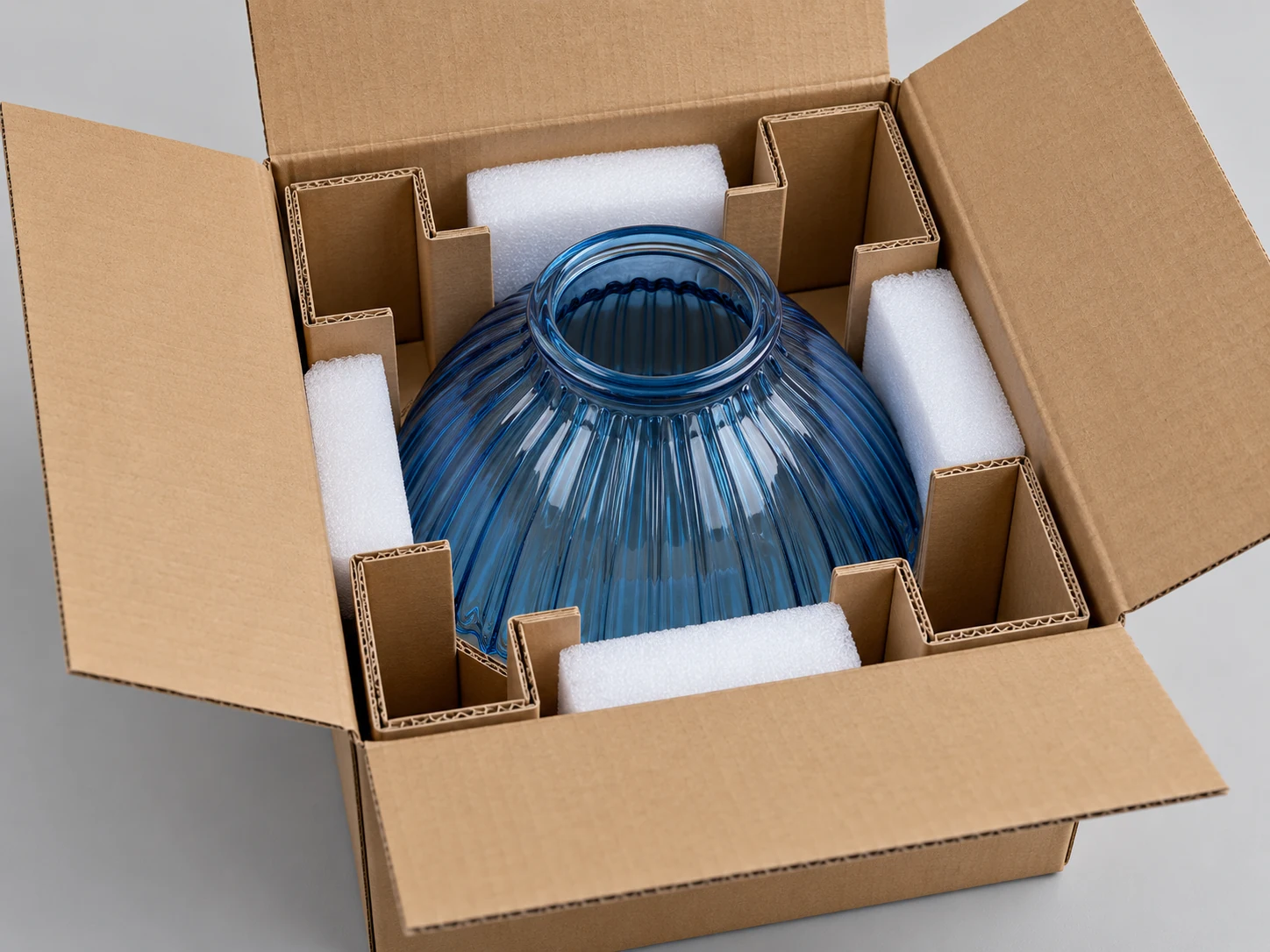 Blue glass shade separated by fitted protective dividers in an open sample carton
