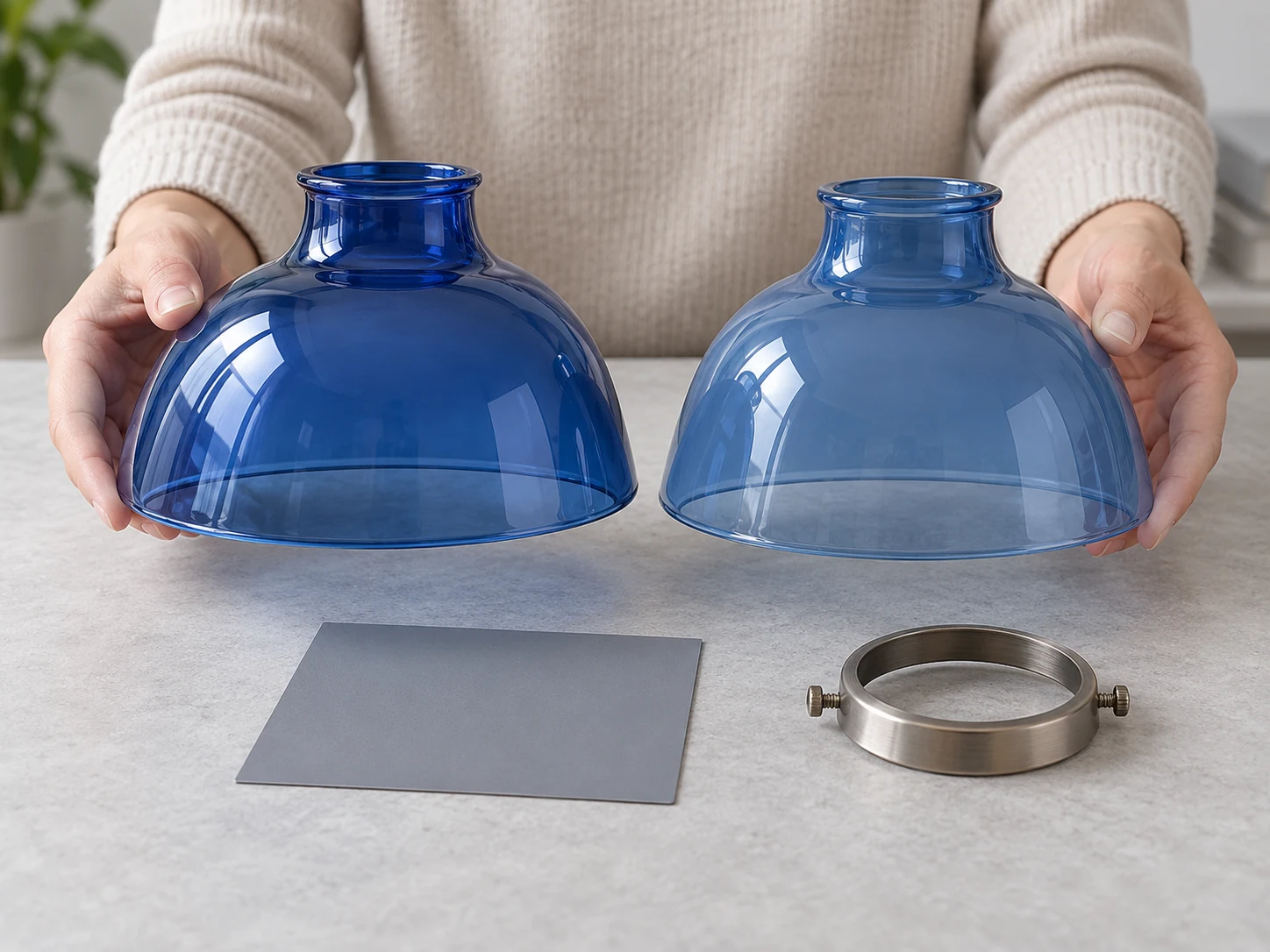 Hands comparing two blue glass shade samples beside a neutral color reference
